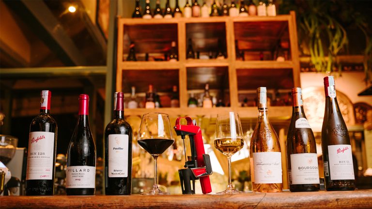 Red and white wines, glasses and the red Coravin wine preservation system on the bar at Muse