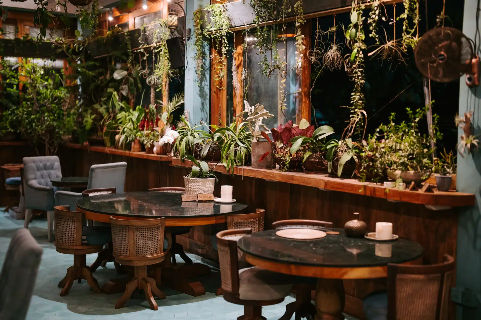 Warmly lit tables beside tropical plants at Muse Ubud in the evening