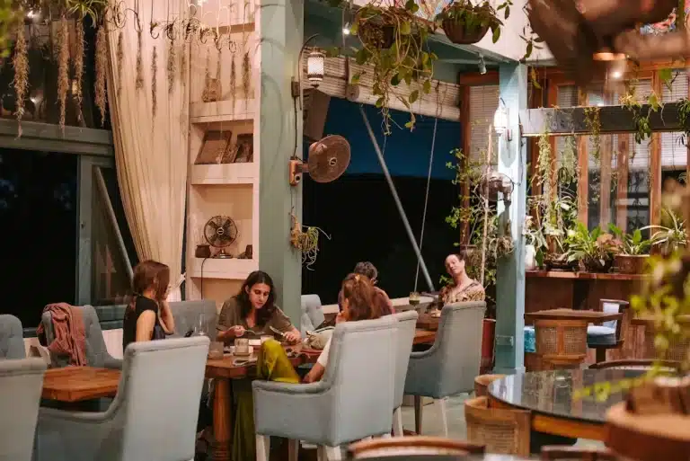 Guests dining in the evening at Muse Café & Art in Ubud, among linen curtains and hanging plants
