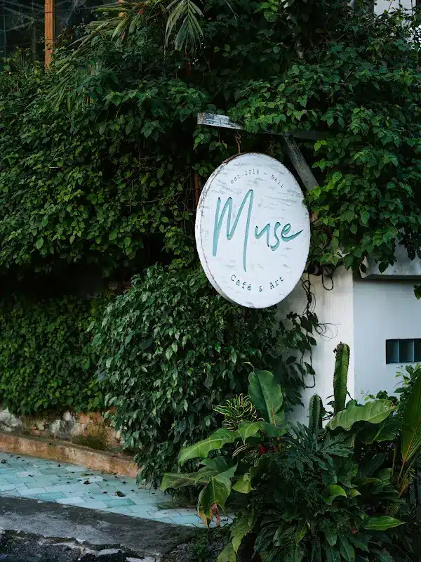 The round Muse sign on the bougainvillea-covered wall at the entrance on Jalan Sri Wedari